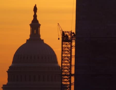A bucket is lifted by scaffolding workers at the Washington Monument (R) at sunrise in Washington March 15, 2013. The U.S. Capitol is seen at left. REUTERS/Gary Cameron