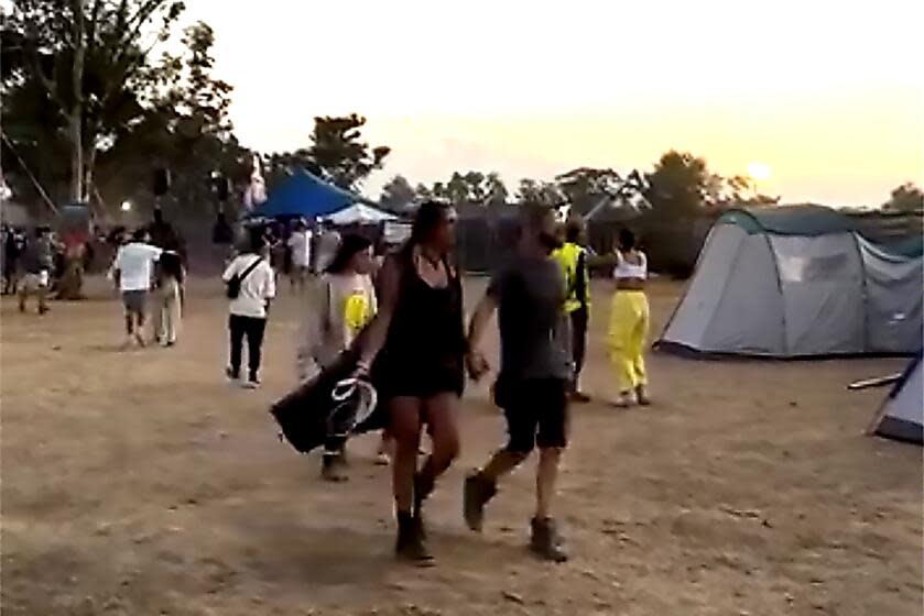 People attend the open-air Tribe of Nova music festival as Hamas fired rockets explode in the background