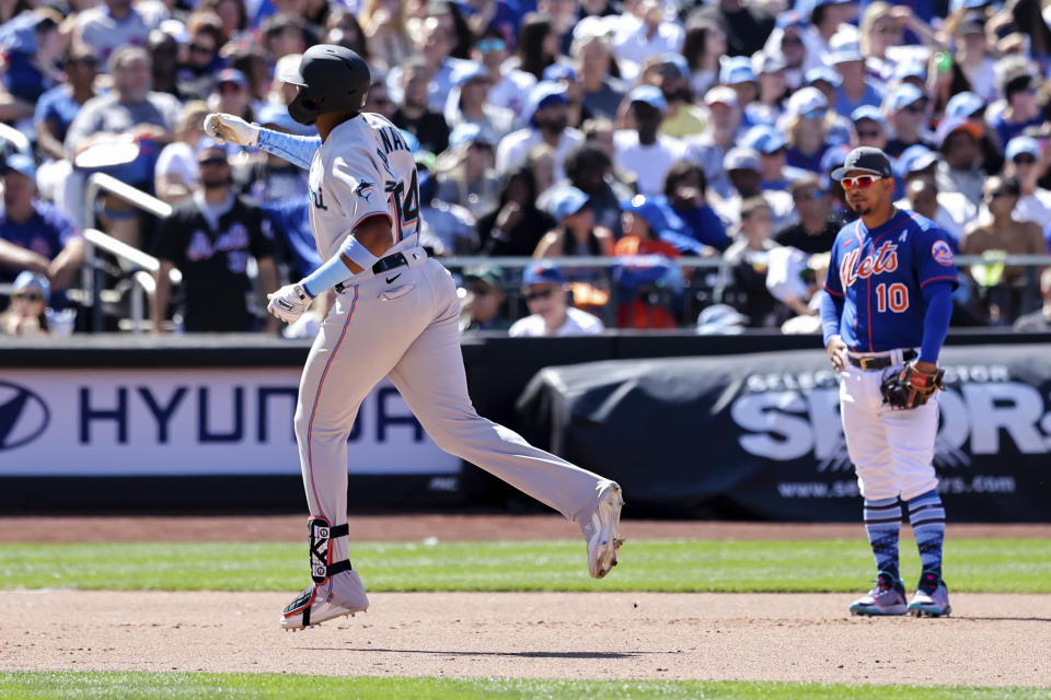 Miami Marlins' Jerar Encarnacion, left, signals to the dugout after hitting a grand slam against New York Mets relief pitcher Seth Lugo as Mets third baseman Eduardo Escobar (10) watches during the seventh inning of a baseball game, Sunday, June 19, 2022, in New York. (AP Photo/Jessie Alcheh)