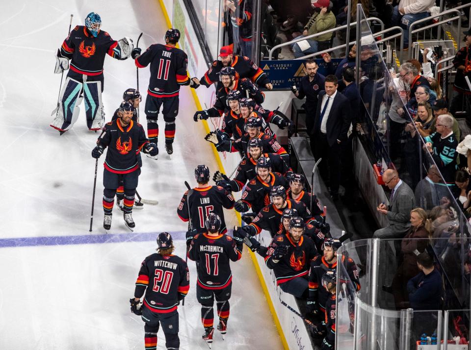 Coachella Valley Firebirds players celebrate a coach by Alexander True during the first period of game two of the Western Conference Finals at Acrisure Arena in Palm Desert, Calif., Saturday, May 27, 2023. 