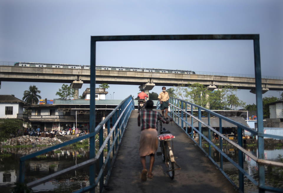 A metro train runs behind as a man wearing mask as a precaution against the coronavirus walks through a bridge in Kochi, Kerala state, India, Thursday, April 22, 2021. India reported a global record of more than 314,000 new infections Thursday as a grim coronavirus surge in the world's second-most populous country sends more and more sick people into a fragile health care system critically short of hospital beds and oxygen. (AP Photo/R S Iyer)