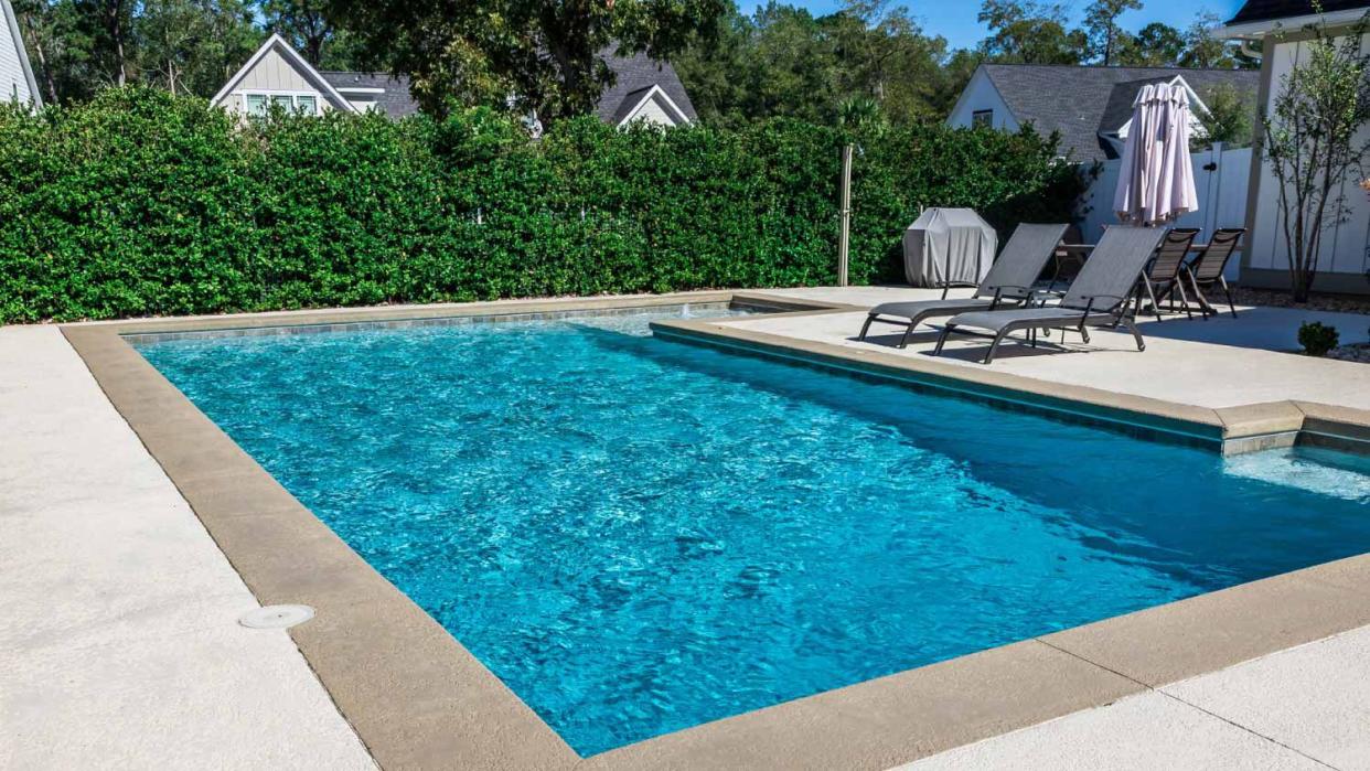 A rectangular new swimming pool with tan concrete edges