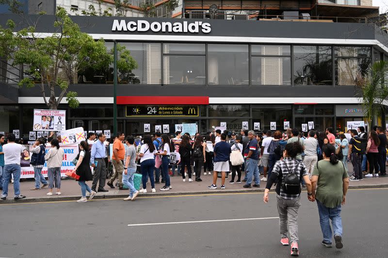 People protest outside a closed McDonald's restaurant, after the the deaths of two teenaged employees, in Lima