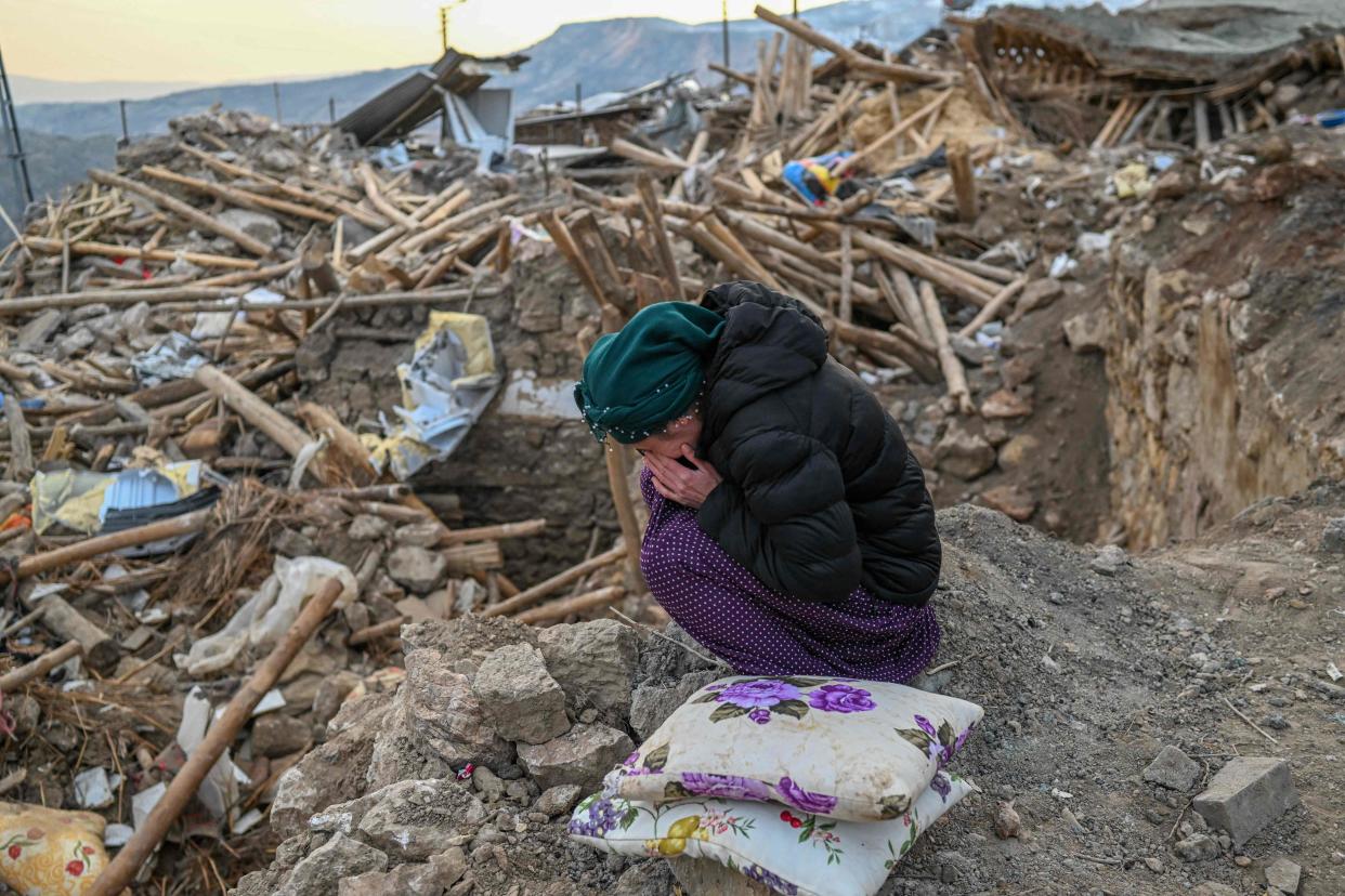 A woman cries on Feb. 19, 2023, as she sits atop the rubble of her collapsed house in Yaylakonak village in Adiyaman district, a Kurdish alevi community village where 108 people died and 170 houses collapsed after a 7.8-magnitude earthquake struck parts of Turkey and Syria.