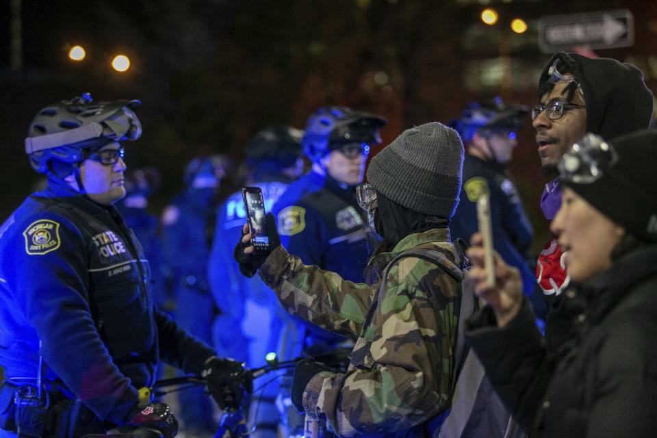 A protester records police officers on their phone as they block the on ramp to Interstate 196 during a march downtown Grand Rapids, Mich., on Saturday, April 16, 2022. Activists have held protests for four straight days since the release of a video showing 26-year-old Congolese immigrant Patrick Lyoya being shot and killed by a Grand Rapids police officer while resisting arrest during a traffic stop on April 4. (Daniel Shular/The Grand Rapids Press via AP)