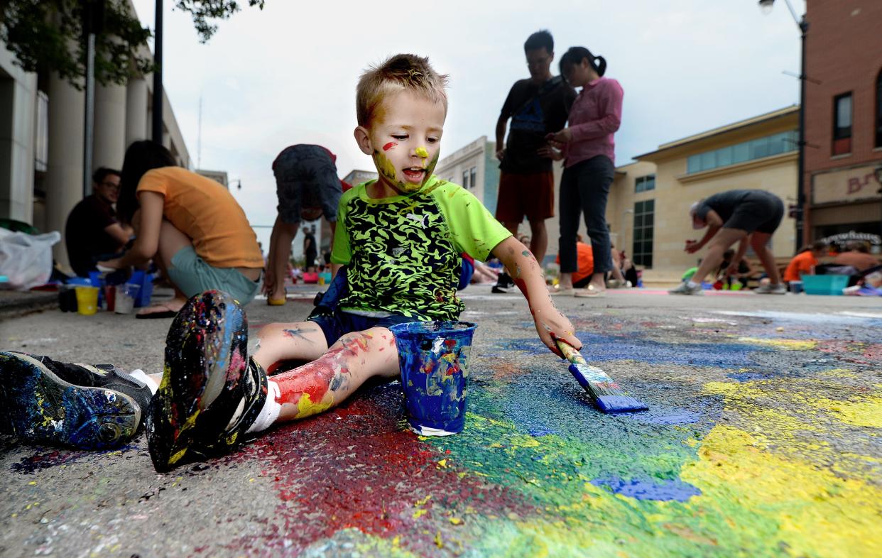 Koleson Silva, 3, of Springfield gets as much paint on himself as he gets on the street as he paints on Washington Street between Sixth and Seventh streets on Saturday during the "Paint the Street" event.