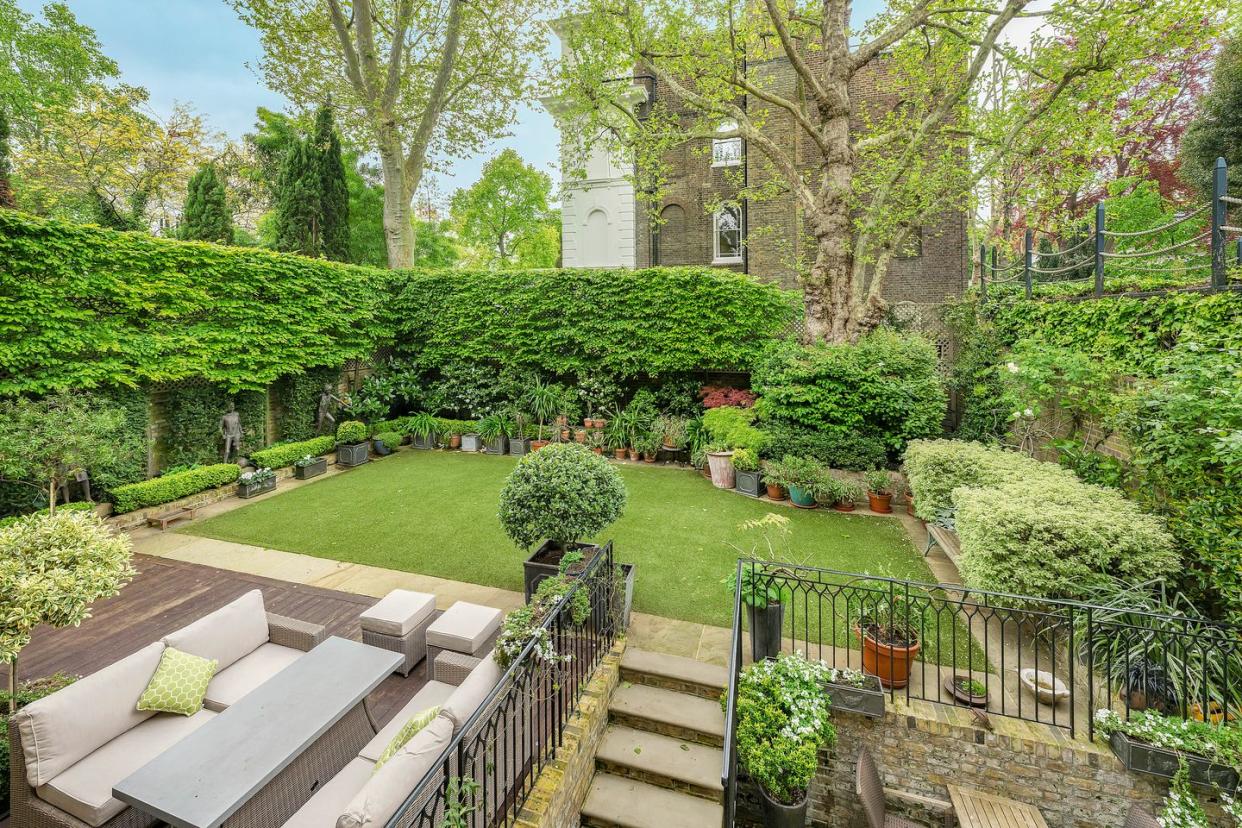 a view of the house's prim and proper english garden with statues and manicured hedges