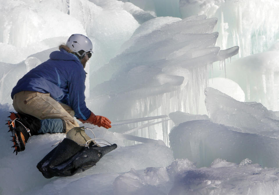 In this photo taken Wednesday Jan. 8, 2014 Cory Livingood places icicles on the top of his ice castle at the base of the Loon Mountain ski resort in Lincoln, N.H. The ice castle begins to grow in the fall when the weather gets below freezing and thousands of icicles are made and harvested then placed around sprinkler heads and sprayed with water. The castle will continue to grow as long as the temperatures stay below freezing. (AP Photo/Jim Cole)