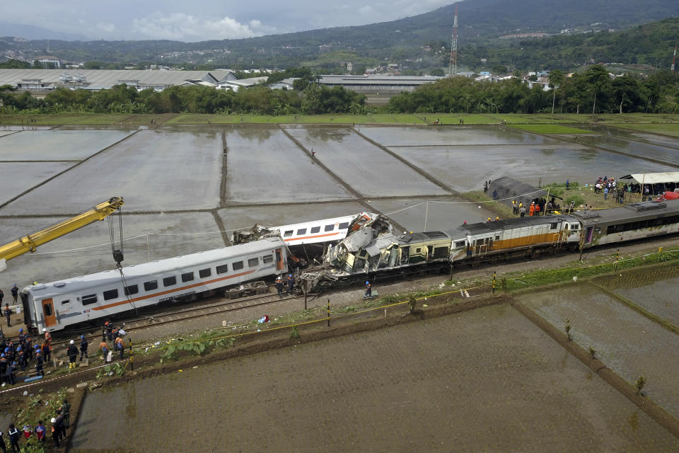 Rescuers inspect the wreckage after a collision between two trains in Cicalengka, West Java, Indonesia, Friday, Jan. 5, 2024. The trains collided on Indonesia's main island of Java on Friday, causing several carriages to buckle and overturn, officials said. (AP Photo/Achmad Ibrahim)