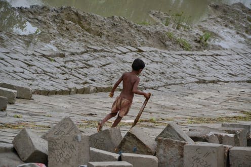 <span class="caption">A Bangladeshi boy walks along a riverbank protected from climate-driven erosion by concrete blocks.</span> <span class="attribution"><span class="source">Sonja Ayeb-Karlsson</span>, <span class="license">Author provided</span></span>