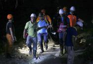 Rescuers carry a body of a victim after being dug out of the rubble following a landslide that buried dozens of homes in Naga city, Cebu province central Philippines on Thursday Sept. 20, 2018. A landslide set off by heavy rains buried homes under part of a mountainside in the central Philippines on Thursday, and several people are feared buried, including two who sent text messages seeking help. (AP Photo/Bullit Marquez)