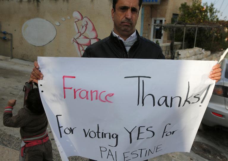 A Palestinian holds a poster as he thanks French lawmakers during a rally in the West Bank city of Ramallah, on December 2, 2014