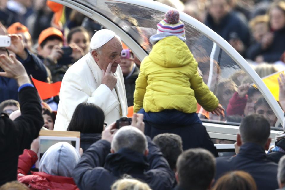 Pope Francis touches his cheek as he is driven through the crowd during his weekly general audience, in St. Peter's Square, at the Vatican, Wednesday, Jan. 15, 2014. (AP Photo/Andrew Medichini)