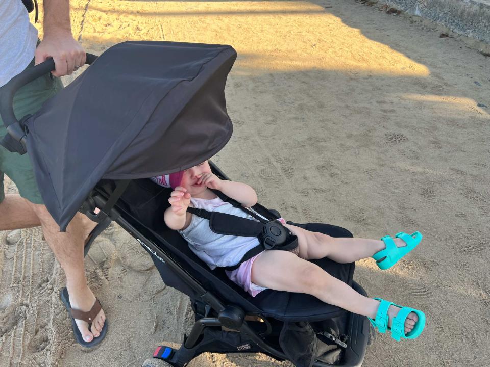 A child sitting in a stroller that is upset.