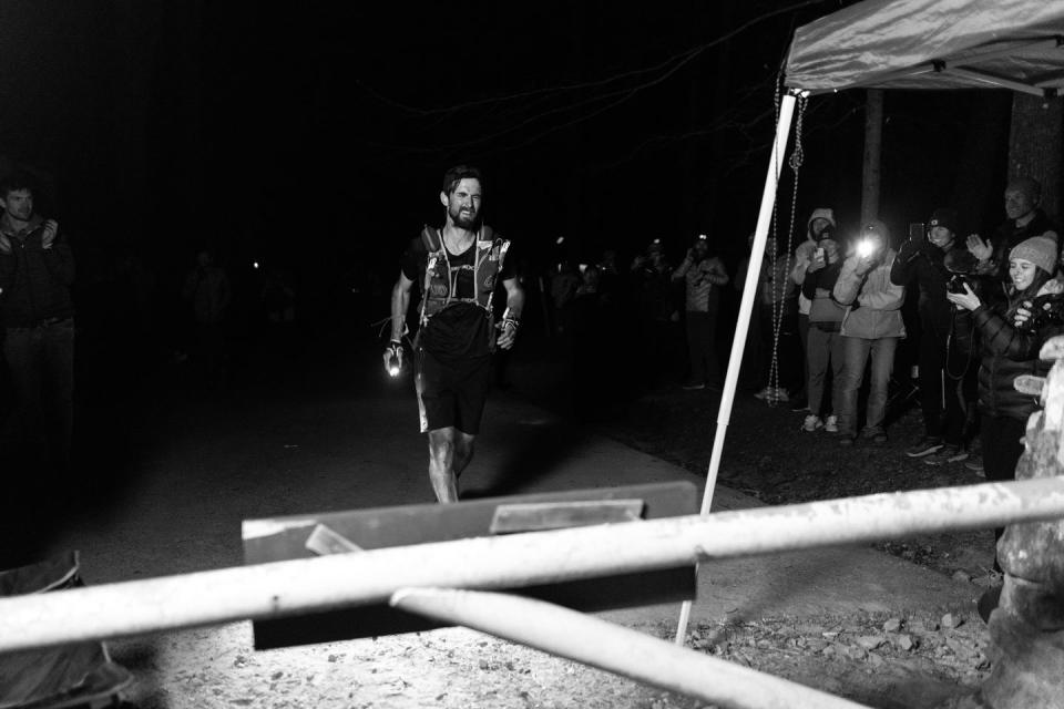 an exhausted trail runner arrives at a finish line in the dark