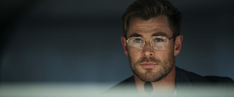 Chris Hemsworth in glasses with a microphone in front of him