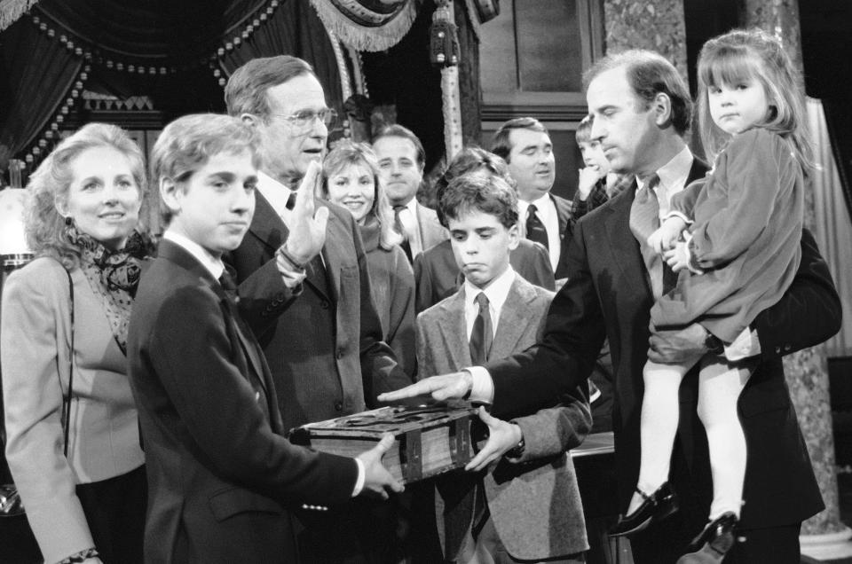 Sen. Joe Biden, D-Del., holds his daughter Ashley while taking a mock oath of office from Vice President George Bush during a ceremony on Capitol Hill, in Washington, Jan. 3, 1985. Biden's sons Beau and Hunter hold the bible during the ceremony. (AP Photo/Lana Harris)