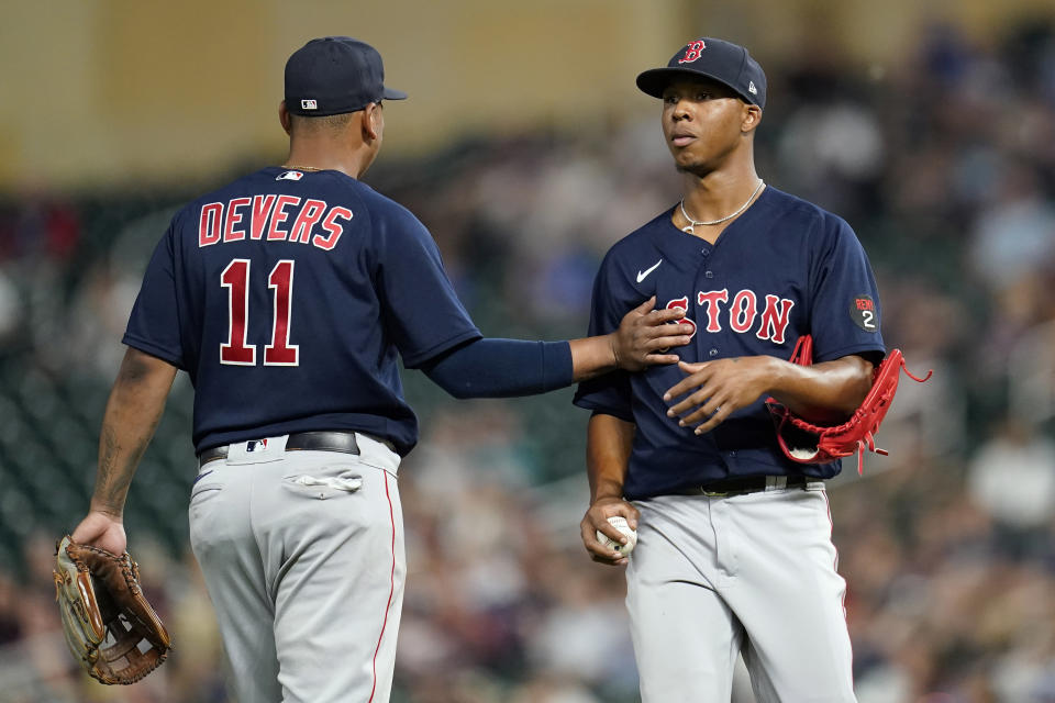 Boston Red Sox starting pitcher Brayan Bello, right, is supported by third baseman Rafael Devers (11), left, after allowing a run during the fourth inning of a baseball game against the Minnesota Twins, Monday, Aug. 29, 2022, in Minneapolis. (AP Photo/Abbie Parr)