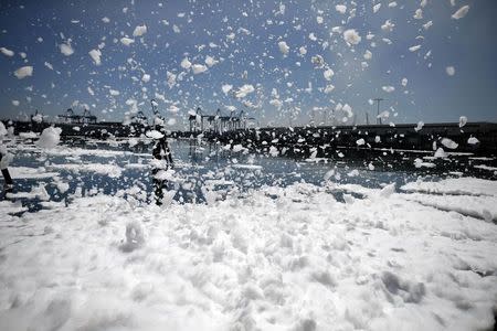 Foam swirls in the harbor as firefighters douse a smouldering dock fire that broke out on Monday evening and burned about 150 feet (45 meters) of a wharf area at the Port of Los Angeles, California September 23, 2014. REUTERS/Lucy Nicholson