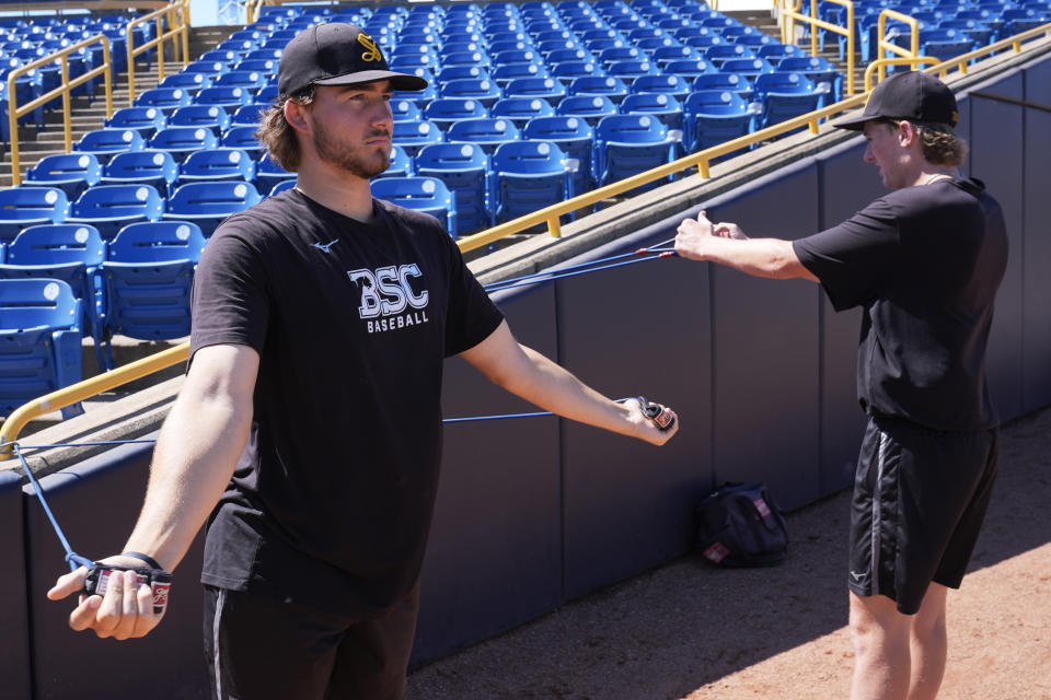 Birmingham-Southern pitchers Ben Hoover, left, and Jayson Barber, right, stretch during practice Thursday, May 30, 2024, in Eastlake, Ohio. On Friday, the Panthers will continue an unexpected, uplifting season that has captured hearts across the country by playing in the Division III World Series on the same day the liberal arts college founded on the eve of the Civil War shuts its doors. (AP Photo/Sue Ogrocki)