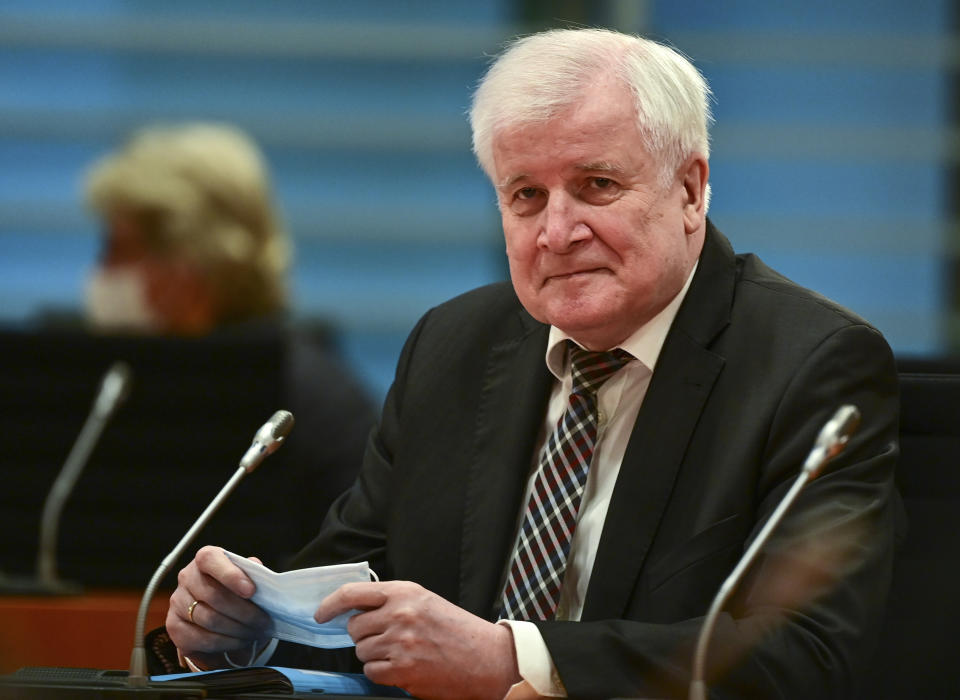 German Interior Minister Horst Seehofer holds a medical mask prior to the start of the weekly cabinet meeting at the Chancellery in Berlin, German, Wednesday, Oct. 20, 2021. (Ina Fassbender/Pool Photo via AP)