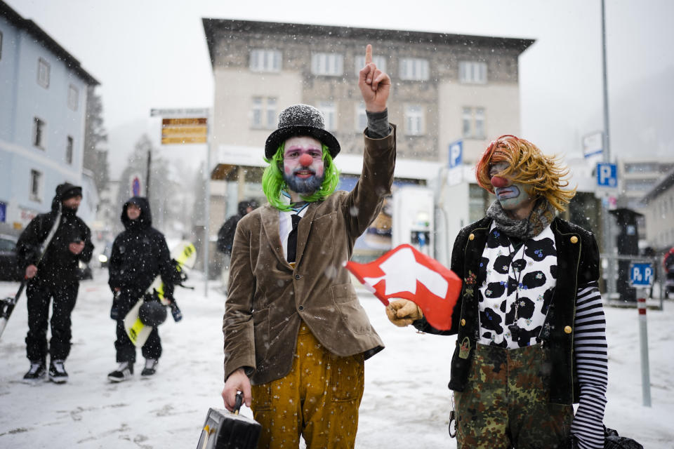 Two man made up as clowns attend a demonstration against the annual meeting of the World Economic Forum in Davos, Switzerland, Sunday, Jan. 15, 2023. The annual meeting of the World Economic Forum is taking place in Davos from Jan. 16 until Jan. 20, 2023. (AP Photo/Markus Schreiber)