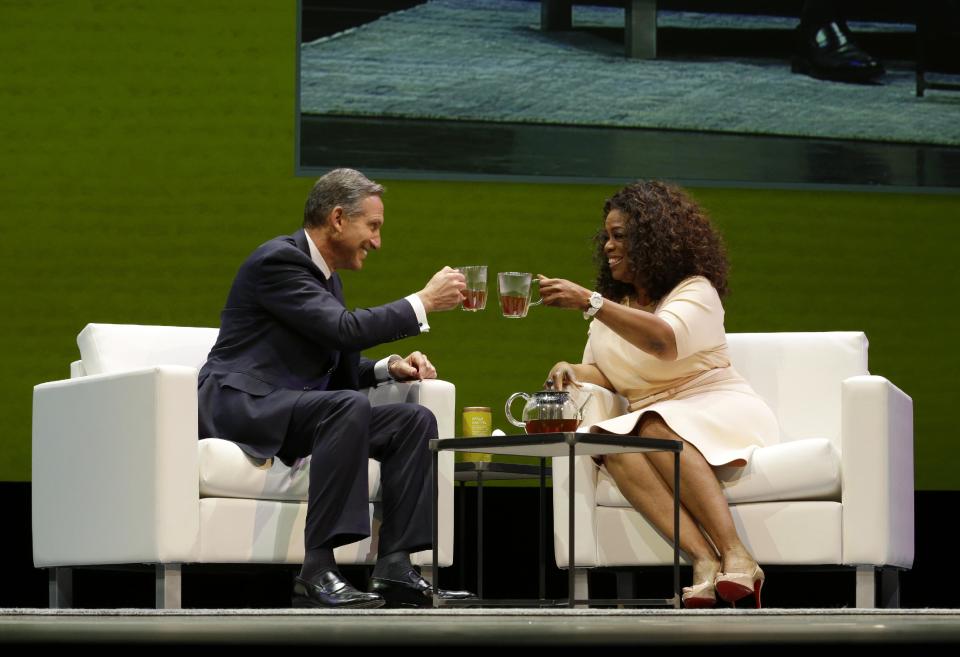 Howard Schultz, left, chairman and CEO of Starbucks Coffee Company, clinks tea cups with Oprah Winfrey, right, to announce their partnership to offer Teavana Oprah Chai tea, Wednesday, March 19, 2014, at Starbucks' annual shareholders meeting in Seattle. (AP Photo/Ted S. Warren)