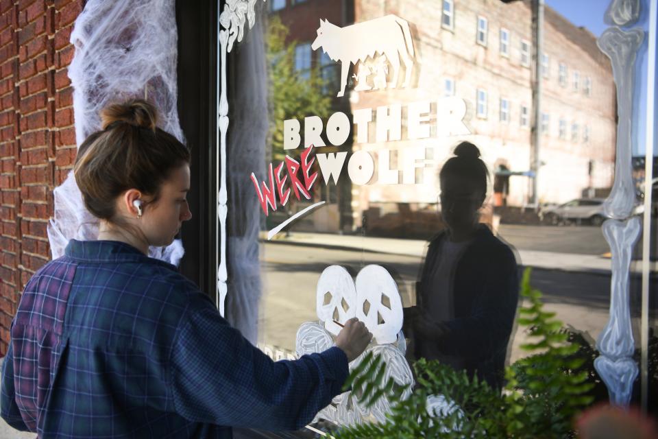 Casey Clark paints the window of the Halloween themed pop-up bar Brother Werewolf at Brother Wolf in the Old City, Thursday, Oct. 6, 2022.