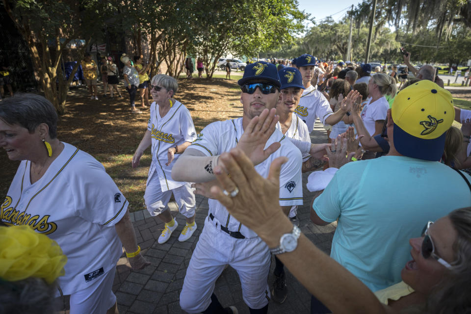 Savannah Bananas players greet fans waiting in line before the gates open Tuesday, June 7, 2022, in Savannah, Ga. (AP Photo/Stephen B. Morton)