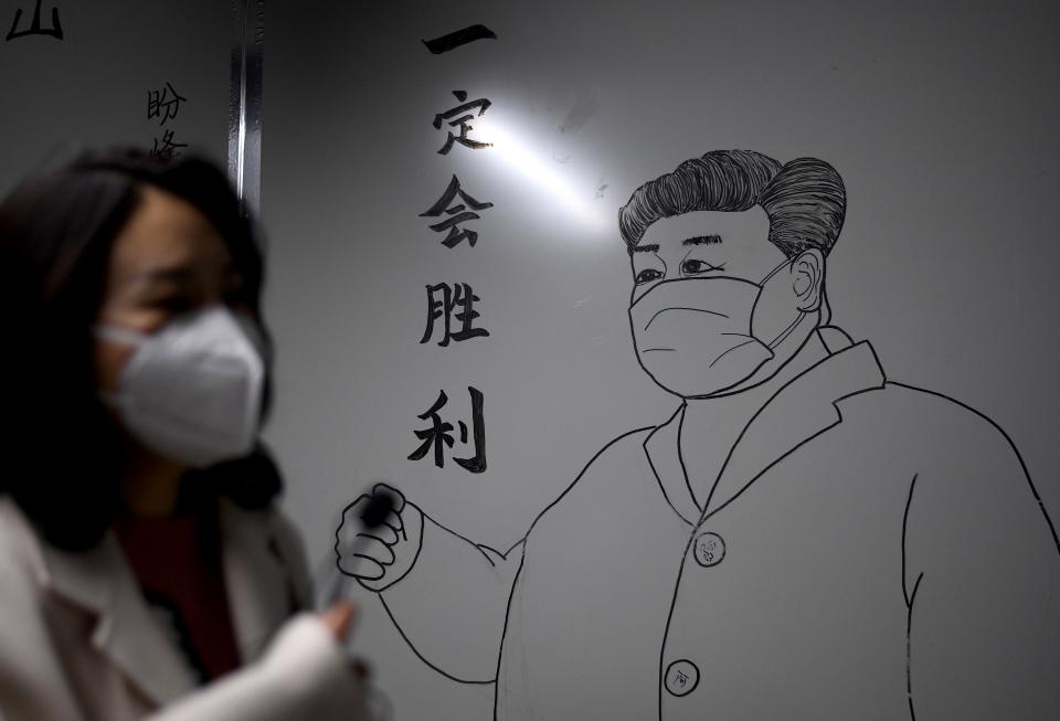 A woman wearing a face mask walks in front of a drawing of Chinese President Xi Jinping on a wall at the Leishenshan Hospital that had offered beds for coronavirus patients in Wuhan, in Chinas central Hubei province on April 11, 2020. (Photo by Noel Celis / AFP) (Photo by NOEL CELIS/AFP via Getty Images)