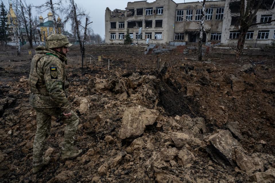 A Ukrainian officer walks amid the devastation caused by a Russian glide bomb that landed in the village of Petropavlivka on Feb. 13, 2024.