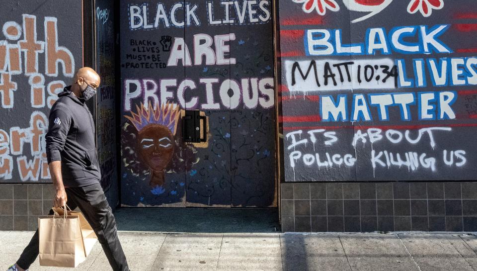 A person walks by a boarded-up shop in Oakland, California on February 12, 2021. - Racial minorities have borne the brunt of the Covid-19 pandemic in the United States, with higher rates of death, unemployment and business failure, and less success obtaining federal government assistance intended to provide relief. (Photo by JOSH EDELSON / AFP) (Photo by JOSH EDELSON/AFP via Getty Images)