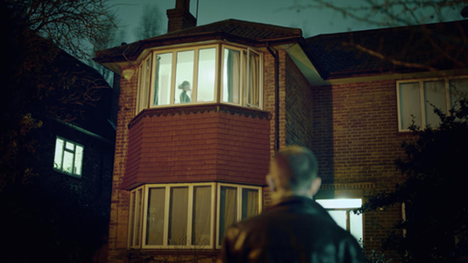 A file image of a man watching a woman through a window at night.