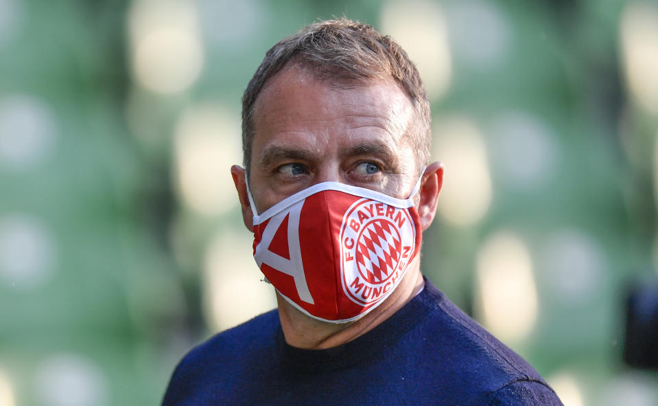 Bayern's head coach Hansi Flick watches behind a Bayern face mask prior the German Bundesliga soccer match between Werder Bremen and Bayern Munich in Bremen, Germany, Tuesday, June 16, 2020. Bayern became champion for the 30th time in Germany after winning the match. Because of the coronavirus outbreak all soccer matches of the German Bundesliga take place without spectators. (AP Photo/Martin Meissner, Pool)