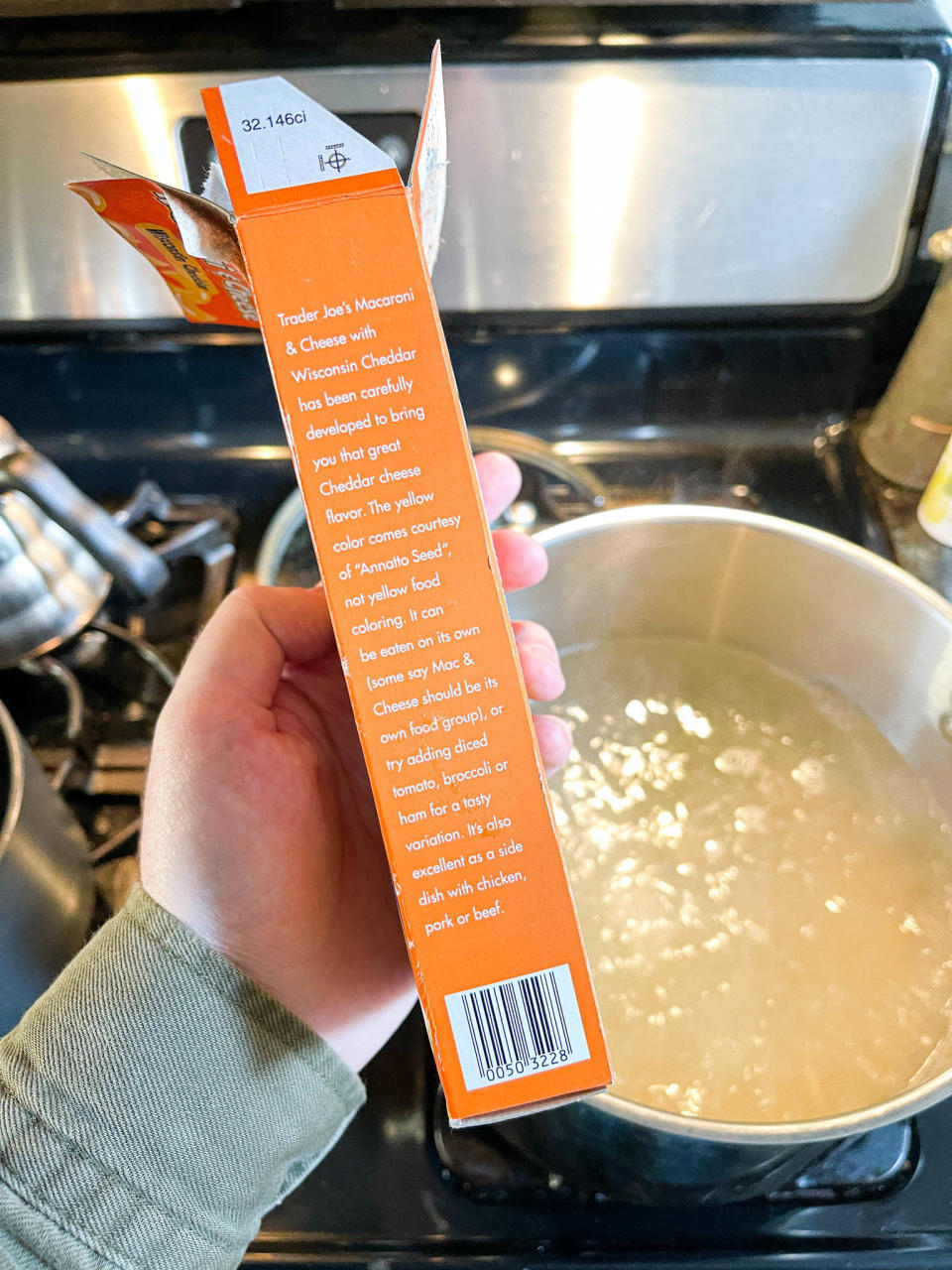 Author holding up the Trader Joe's box in front of a large pot of boiling water