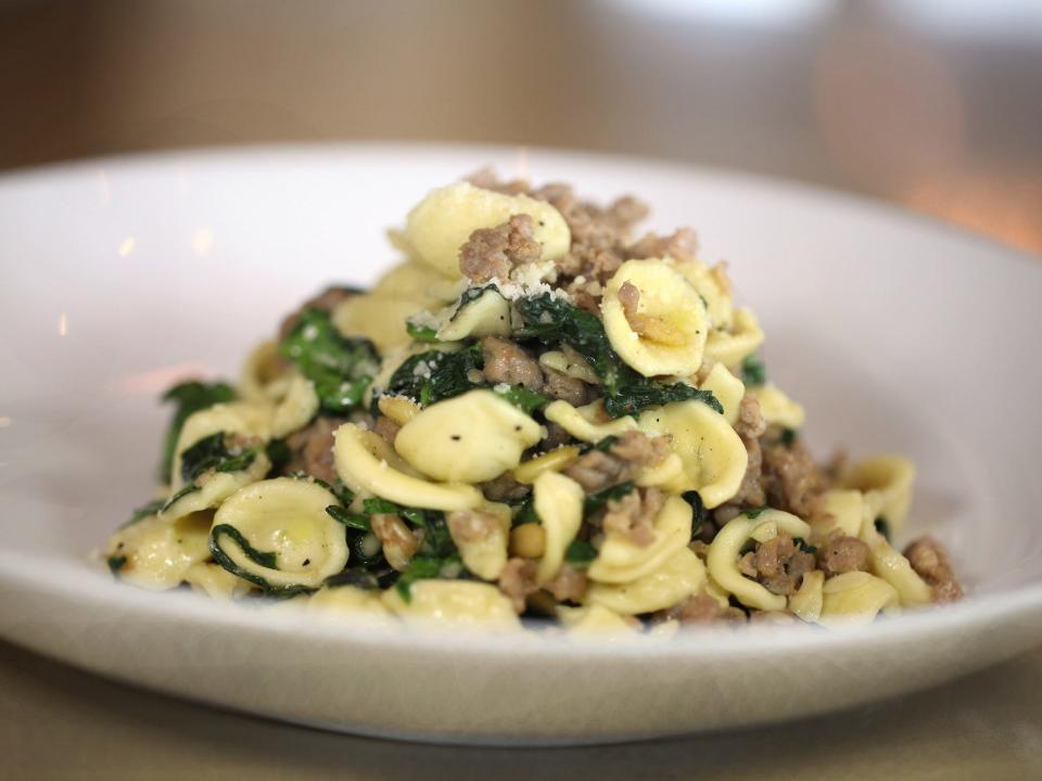 a plate of orecchiette with greens and sausage