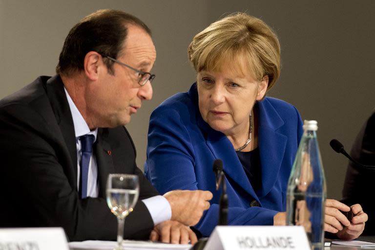 German Chancellor Angela Merkel (R) and French President Francois Hollande chat during a press conference following a European Union (EU) extraordinary summit "Growth and Employment" on October 8, 2014 in Milan