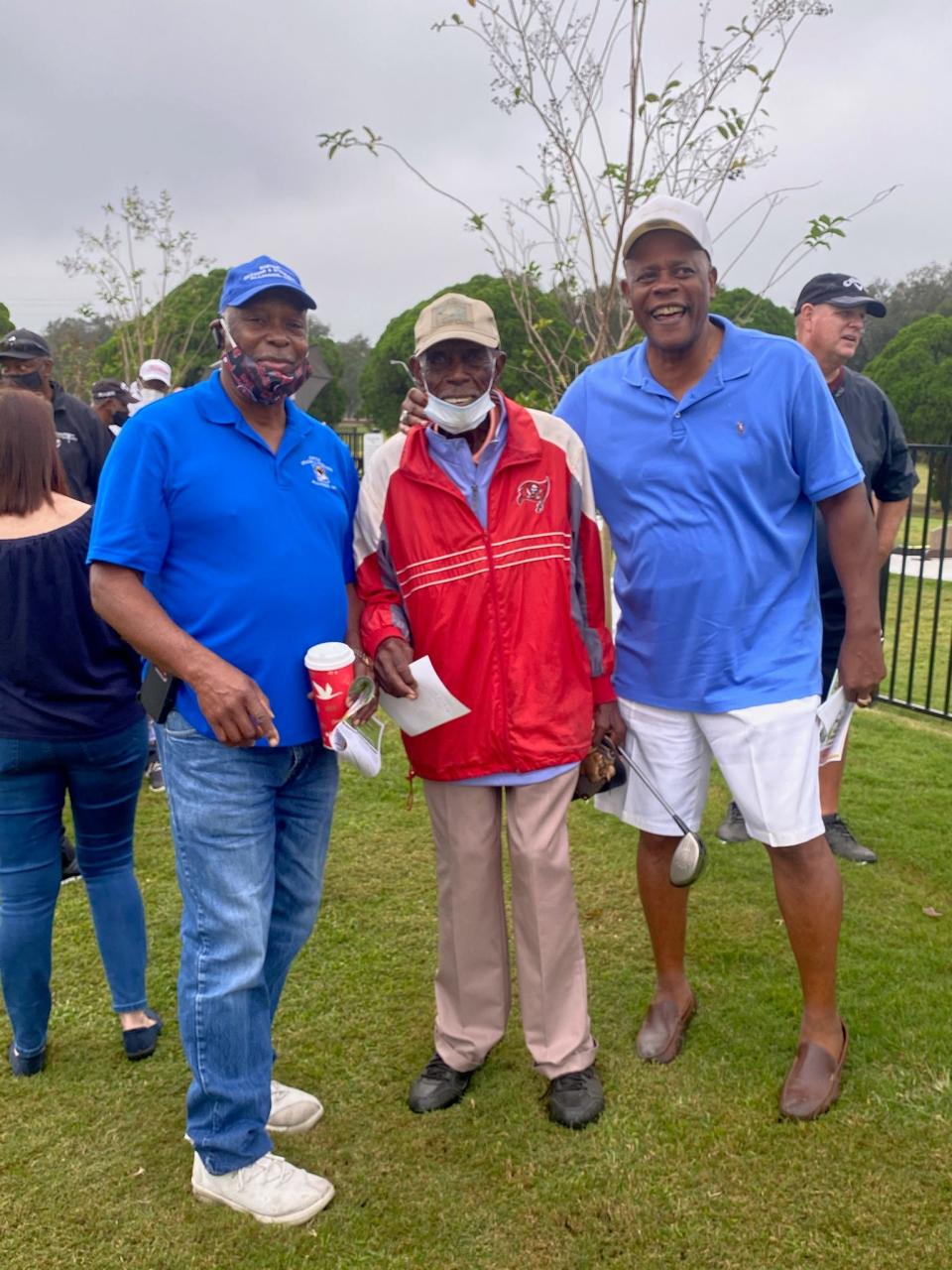 Herbert Dixon (middle) stands with Carver Young (l) and Larry Mitchel at a golf tournament. Dixon still golfs at the age of 102.