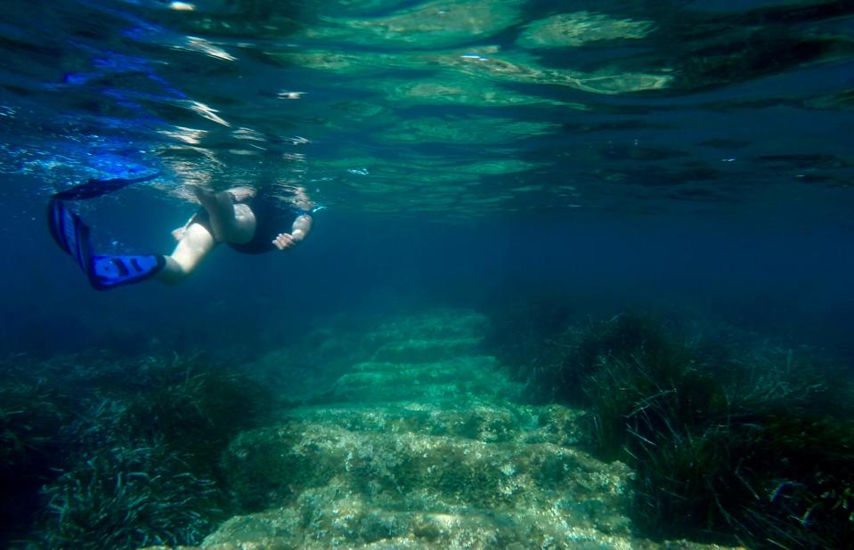 Yiannis Violaris of the Cyprus Antiquities Department snorkels over submerged stone remains of a 2,400 year-old harbor said to be built Alexander the Great's successors near the modern-day resort town of Limassol, Cyprus.