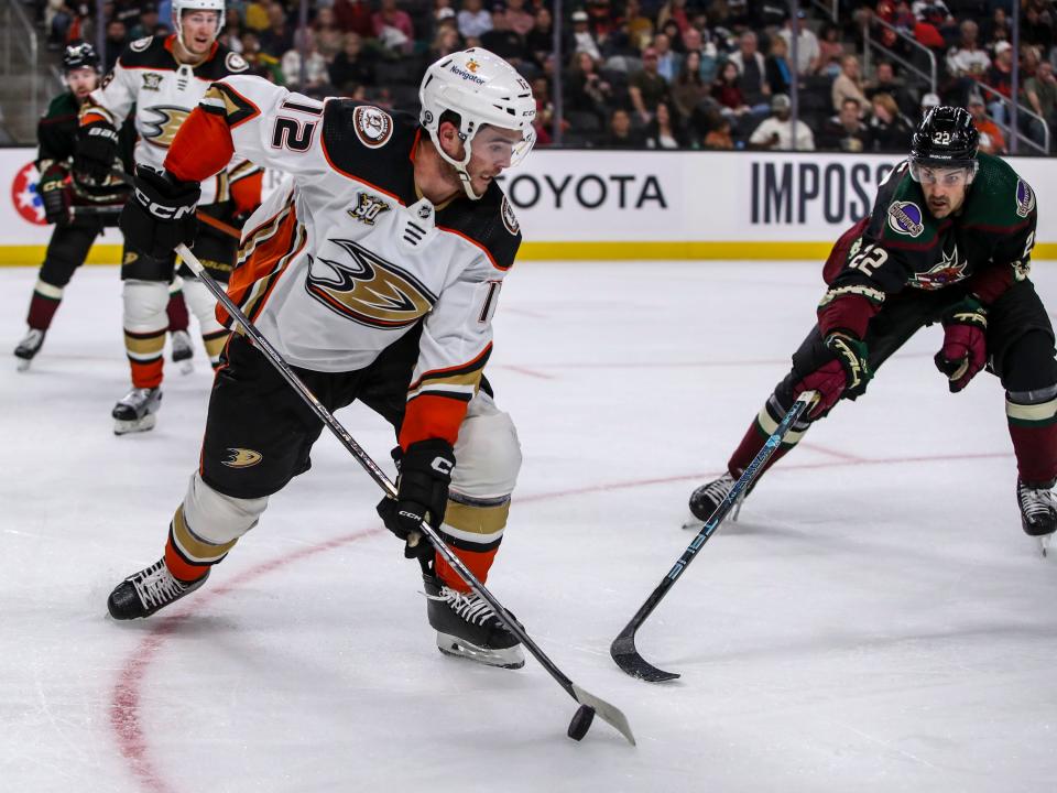 Anaheim Ducks defenseman Scott Harrington (12) works to clear the puck as Arizona Coyotes forward Jack McBain (22) closes in during the second period of their exhibition game at Acrisure Arena in Palm Desert, Calif., Sunday, Oct. 1, 2023.