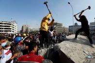 Iraqi demonstrators smash concrete walls at Sinak Bridge during the ongoing anti-government protests, in Baghdad
