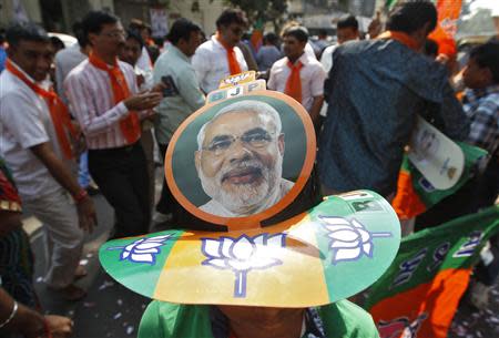 A supporter wearing a cap carrying a picture of Gujarat's chief minister and Hindu nationalist Narendra Modi, the prime ministerial candidate for India's main opposition Bharatiya Janata Party (BJP), attends the celebrations outside the party's headquarters in the western Indian city of Ahmedabad December 8, 2013. REUTERS/Amit Dave