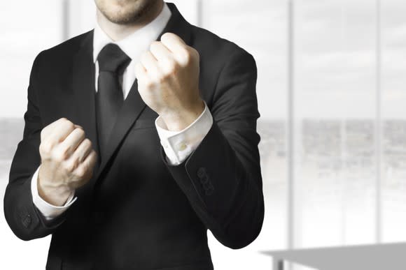 A man in a suit raises his fists to fight.