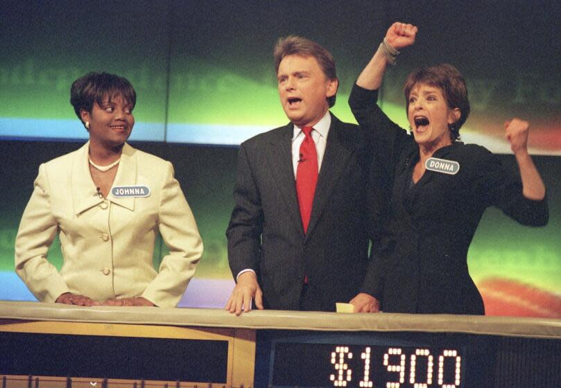 FILE - Johnna Goodwin, left, watches as Donna Handel, right, reacts after winning on "Wheel of Fortune," with host Pat Sajak during a taping of the game show in Philadelphia on April 17, 1999. The game show was in Philadelphia for the weekend taping a week's worth of shows. Ryan Seacrest will replace the retiring Sajak as host of "Wheel of Fortune." (AP Photo/William Thomas Cain, File)