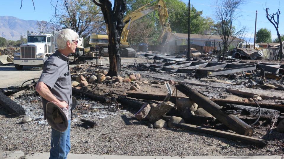 A man looks over ruins after a fire