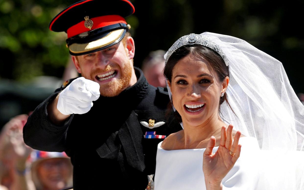 Prince Harry gestures next to his wife Meghan as they ride a horse-drawn carriage after their wedding ceremony at St George's Chapel in Windsor Castle in Windsor, - Damir Sagolj/REUTERS 