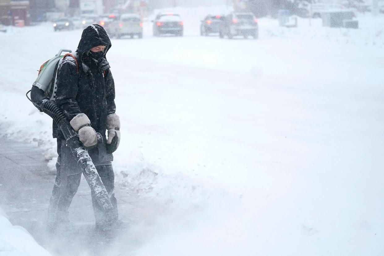 Man blows snow off a sidewalk, in Minneapolis Holiday Travel Weather Minnesota, Minneapolis, United States - 21 Dec 2022