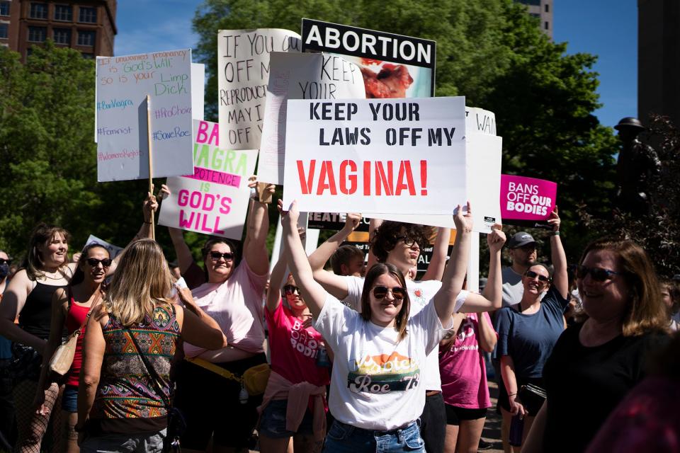 Abortion rights supporters use their signs to cover a few anti-abortion signs Saturday at a Planned Parenthood Advocates of Ohio "Ban Off Our Bodies" rally at the Ohio Statehouse.