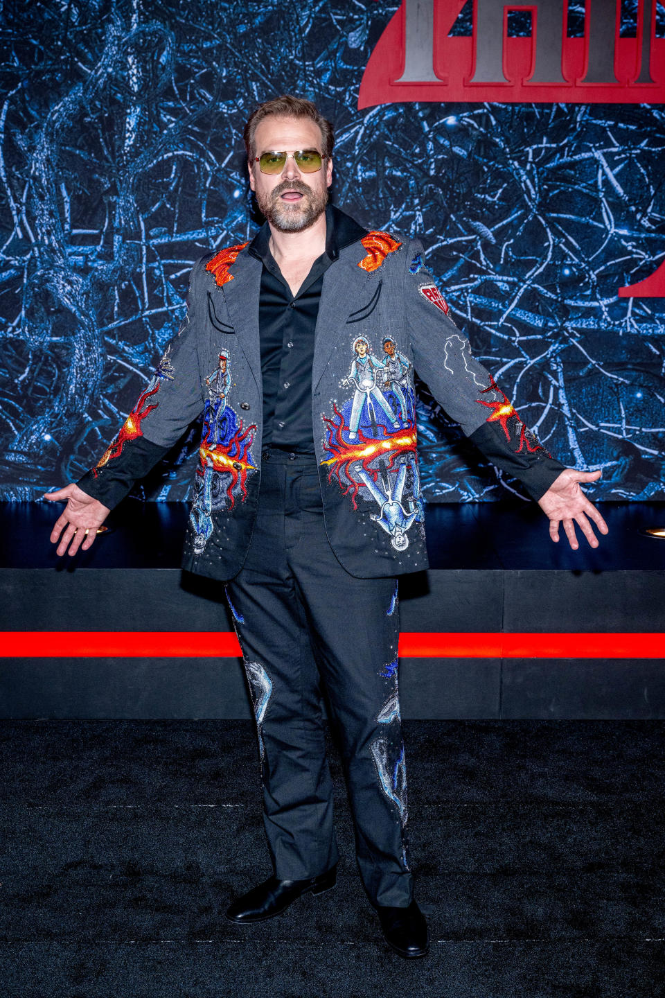 David in a wildly different outfit; this time, it's a custom suit colorfully emblazoned with images from Stranger Things