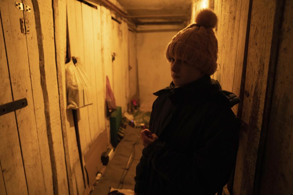 Anya Korotkova, 14, poses in the basement, where she lived with her mother Yulia for more than a year, in Krasnohorivka, Ukraine, Tuesday, Feb. 21, 2023. For months, authorities have been urging civilians in areas near the fighting in eastern Ukraine to evacuate to safer parts of the country. But while many have heeded the call, others -– including families with children -– have steadfastly refused.(AP Photo/Evgeniy Maloletka)